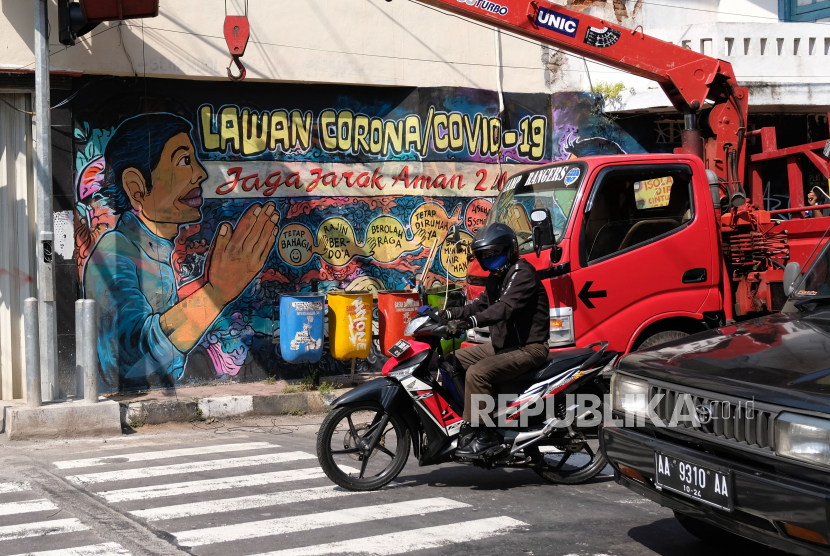 Pengendara motor melintas di dekat mural bertema pandemi Covid-19 di jalan utama Kota Magelang, Jawa Tengah. Wali Kota Magelang Sigit Widyonindito mengemukakan pentingnya pengetatan penerapan protokol kesehatan untuk mencegah Covid-19 menuju kenormalan baru atau new normal.