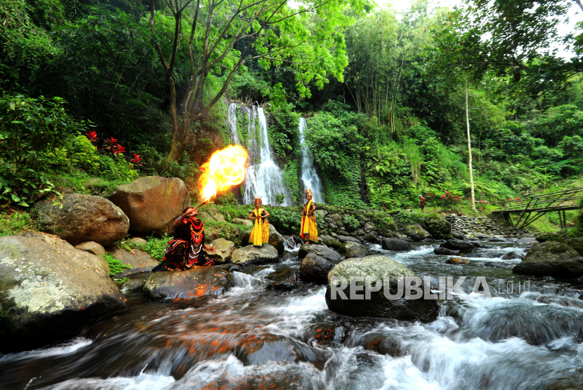 Seniman jaranan buto menyemburkan api dengan latar belakang air terjun Jagir di Banyuwangi, Jawa Timur.