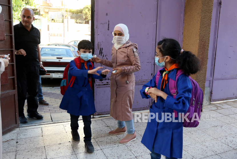  Seorang pengawas menyemprotkan sterilizer ke tangan siswa di Damaskus, Suriah. Kasus Covid-19 di Mediterania Timur melonjak 89 persen pada pekan pertama Januari. Ilustrasi.