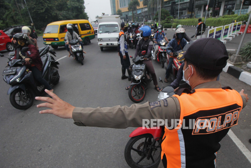 Petugas mengalihkan pengendara motor yang akan masuk ke Surabaya saat penyekatan PPKM Darurat, di Bundaran Waru, Surabaya, Jawa Timur, Sabtu (3/7/2021). Dalam penyekatan itu sejumlah pengendara kendaraan diminta untuk kembali atau tidak masuk ke Surabaya karena tidak memiliki surat vaksinasi COVID-19 atau surat hasil tes COVID-19. 