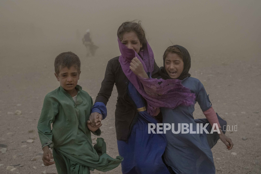 FILE- Anak-anak Afghanistan membawa bantuan sumbangan ke tenda mereka, sementara mereka ketakutan dan menangis akibat badai pasir yang dahsyat, setelah gempa bumi di distrik Zenda Jan. 