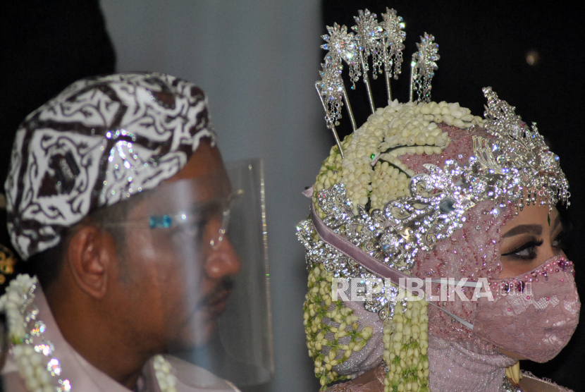Pasangan pengantin menggunakan masker dan alat pelindung wajah saat akad pernikahan. Larangan menggelar hajatan di Lampung Tengah berlaku 9 Juli hingga 10 Agustus 2021. Ilustrasi.