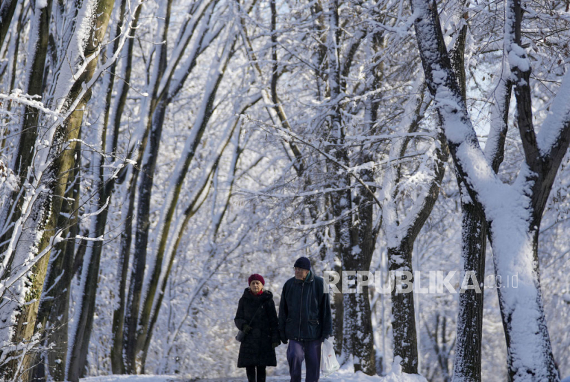 Orang-orang berjalan melalui taman yang tertutup salju di Beograd, Serbia, Sabtu, (20/1/2024). 