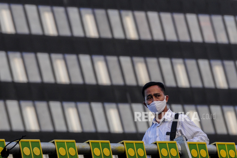 Seorang karyawan swasta berjalan saat jam pulang kerja di kawasan Sudirman, Jakarta. Dinas Tenaga Kerja, Transmigrasi, dan Energi DKI Jakarta menerbitkan aturan terkait pelaksanaan protokol kesehatan di perkantoran atau tempat kerja.