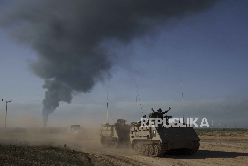 Israeli soldiers on army armored personnel carriers (APC) near the Israeli-Gaza border as smoke rises to the sky in the Gaza Strip, seen from southern Israel, Sunday, Jan. 21, 2024. 