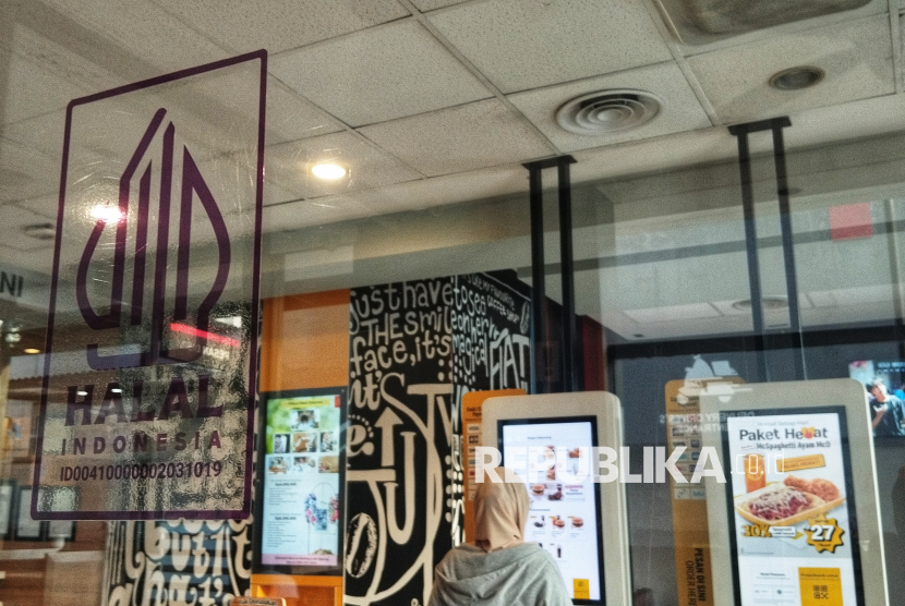 Pelanggan melintas di dekat Logo Halal di Sebuah Restoran Cepat Saji, Jakarta.