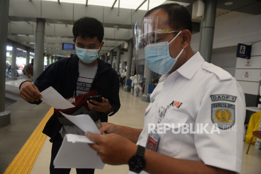 Petugas memberikan hasil Rapid Test Antigen kepada calon penumpang kereta jarak jauh di Stasiun Senen, Jakarta, Senin (21/12).
