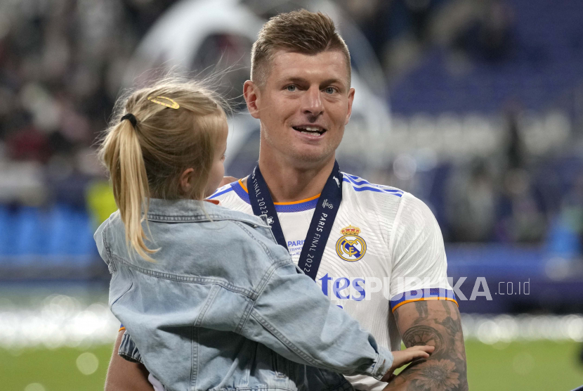  Pemain Real Madrid Toni Kroos menggendong putrinya setelah memenangkan pertandingan sepak bola final Liga Champions antara Liverpool dan Real Madrid di Stade de France di Saint Denis dekat Paris, Ahad (29/5/2022) dini hari WIB.