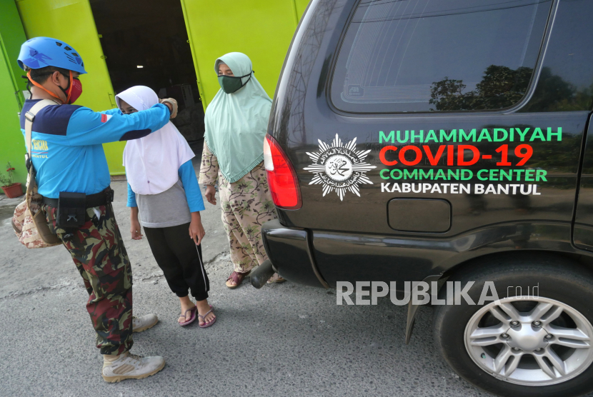 Petugas Muhammadiyah Covid-19 Command Center (MCCC) memberi dan memasangkan masker kepada warga yang tidak menggunakan di Sanden, Bantul, Yogyakarta, Ahad (9/8).