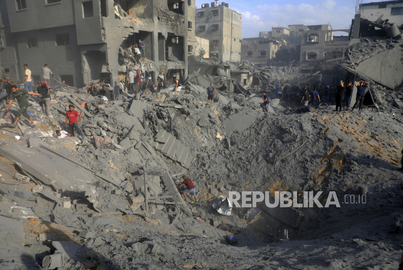 Warga Palestina mencari korban selamat di antara puing-puing bangunan yang hancur pasca serangan Israel di kamp pengungsi Jabaliya di Gaza utara. 