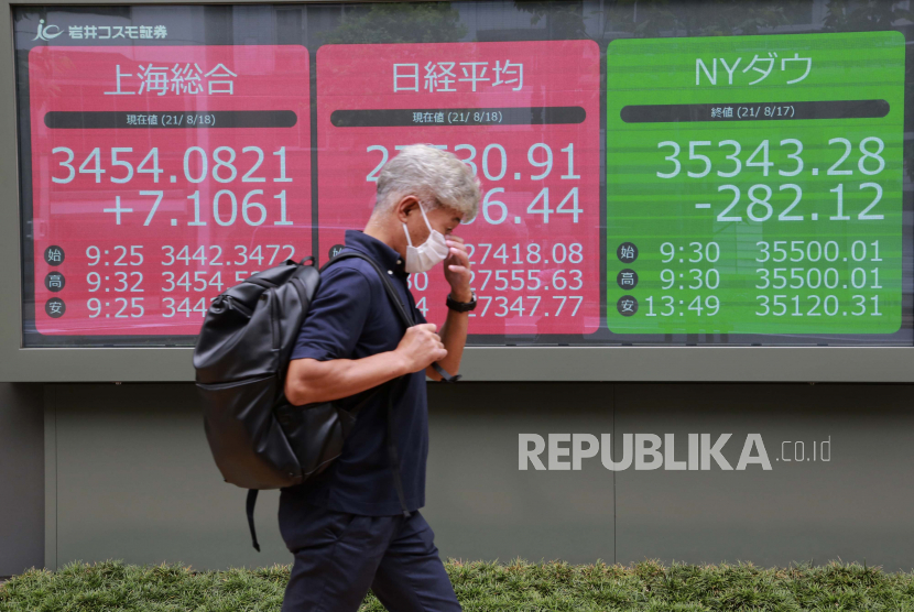  Seorang pria berjalan melewati papan saham elektronik sebuah perusahaan sekuritas di Tokyo, Rabu, 18 Agustus 2021. Pasar saham Asia rebound pada Rabu setelah Wall Street jatuh karena penjualan ritel yang lemah karena investor menunggu pembaruan dari Federal Reserve tentang kemungkinan rencana untuk mengurangi rangsangan AS.