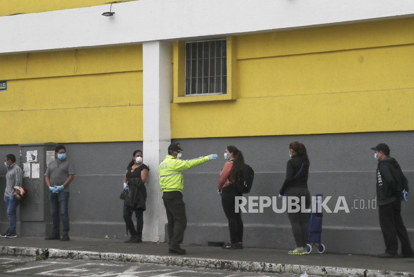 Polisi menginstruksikan pembeli untuk menjaga jarak sosial ketika mengantri memasuki supermarket untuk mencegah penyebaran virus Corona di Quito, Ekuador, Sabtu (28/3). Pemerintah Ekuador telah menyatakan “Darurat Kesehatan,” dengan membatasi pergerakan hanya untuk mereka yang menyediakan layanan pokok