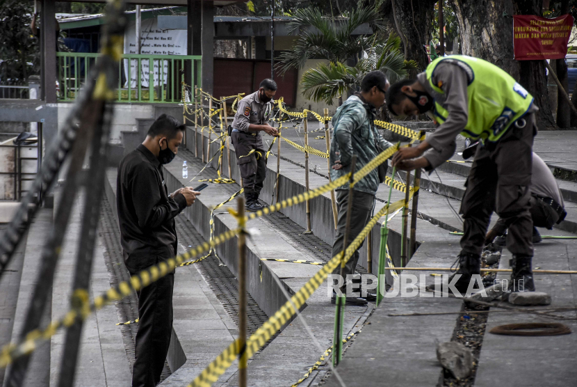 Petugas memasang garis pembatas di area Taman Saparua yang masih ditutup di Jalan Banda, Kota Bandung, Selasa (31/8). Sejumlah taman dan tempat wisata di Kota Bandung masih ditutup untuk umum hingga batas waktu yang belum ditentukan, meski status Pemberlakuan Pembatasan Kegiatan Masyarakat (PPKM) di Kota Bandung telah turun di Level 3.  