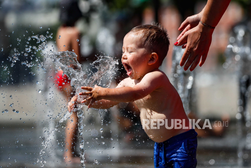 Seorang anak mengusir rasa panas dengan bermain di air mancur taman akibat peningkatan suhu udara.. (Ilustrasi)