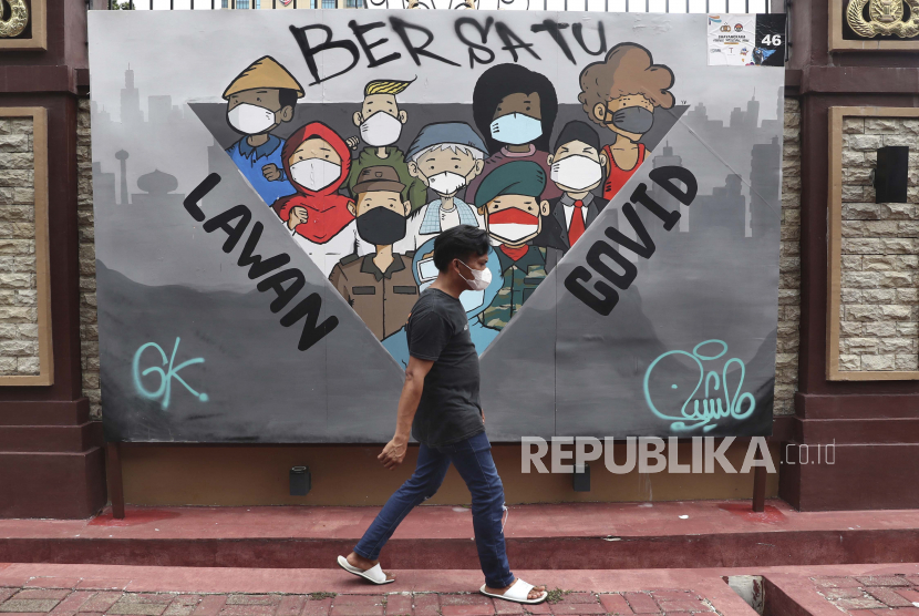 A man walks past a coronavirus-themed mural in Jakarta, Indonesia, Monday, Nov. 29, 2021. Cases of the omicron variant of the coronavirus popped up in countries on opposite sides of the world and many governments rushed to close their borders even as scientists cautioned that it