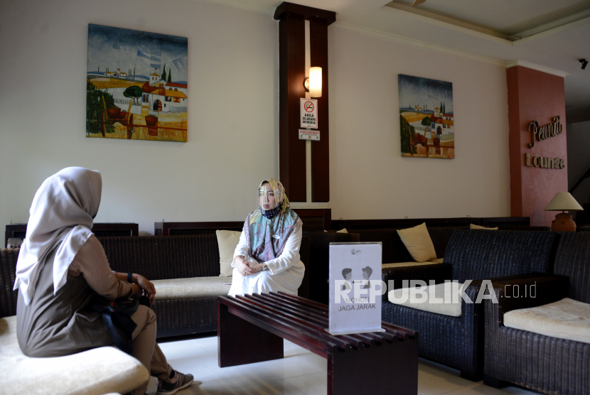 Petugas hotel (kanan) mengenakan alat pelindung wajah (Face shield) dan masker berbincang dengan seorang tamu di Hotel Oasis, Banda Aceh, Aceh, Rabu (15/7/2020). Untuk membangkitkan kembali sektor pariwisata dan ekonomi kreatif yang terdampak pandemi COVID-19, Kementerian Pariwisata dan Ekonomi Kreatif (Kemenparekraf) meminta pengusaha hotel dan restoran menerapkan protokol kesehatan sesuai standar Cleanliness, Health, Safety and Environmental Sustainability (CHSE). 