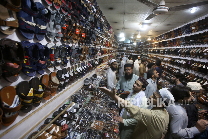 People buy shoes in preparation for the upcoming Eid al-Fitr celebrations at a market, in Peshawar, Pakistan, Thursday, April 20, 2023. Eid al-Fitr marks the end of the Islamic holy month of Ramadan. 
