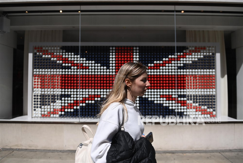 Seorang wanita melewati jendela yang berisi bendera Inggris yang terbuat dari kapsul kopi di London, Inggris, Sabtu (29/4/2023). Penobatan Raja Charles III Inggris berlangsung di Westminster Abbey di London pada 06 Mei 2023. 
