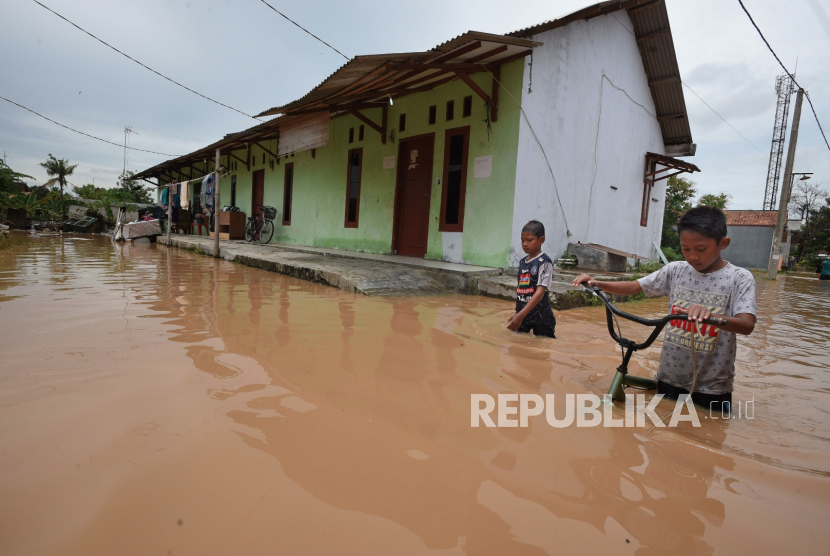 Dua anak menyeberangi banjir di Kampung Margasana, Serang, Banten.