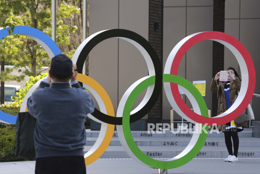 Orang-orang mengambil gambar cincin Olimpiade di Tokyo, Rabu (17/3). Panitia penyelenggara berencana mempersiapkan 300 kamar hotel untuk isolasi atlet dan staf yang terkena Covid-19.