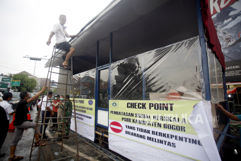 Pekerja menyelesaikan pembuatan posko di Jalan Raya Bogor, Cibinong, Bogor, Jawa Barat