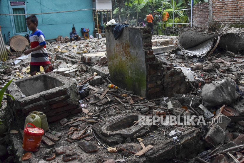 Seorang anak melintasi puing bangunan yang roboh akibat terdampak gempa di Desa Singajaya, Kecamatan Cibalong, Kabupaten Tasikmalaya