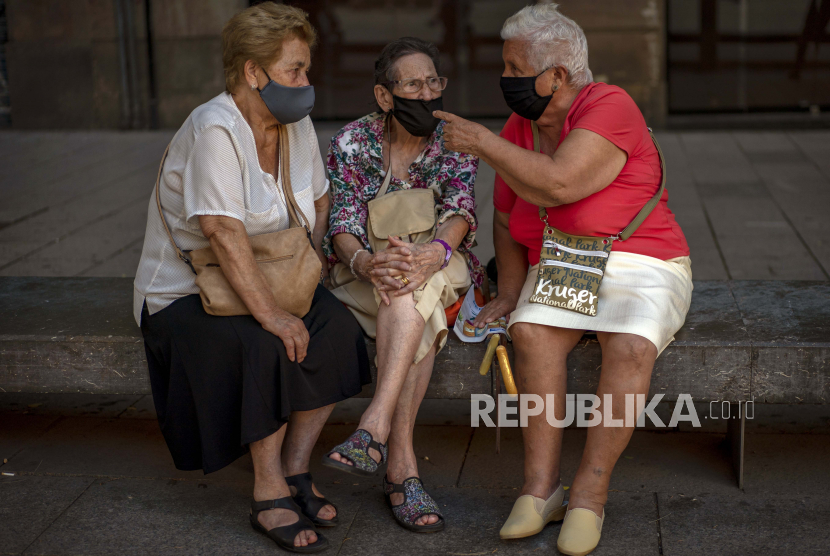 Sejumlah lansia memakai masker wajah untuk mencegah Covid-19 berbincang di sebuah alun-alun di Barcelona, Spanyol, Rabu, (23/9). Spanyol akan memberikan vaksin booster kepada lansia berusia 60 tahun ke atas.