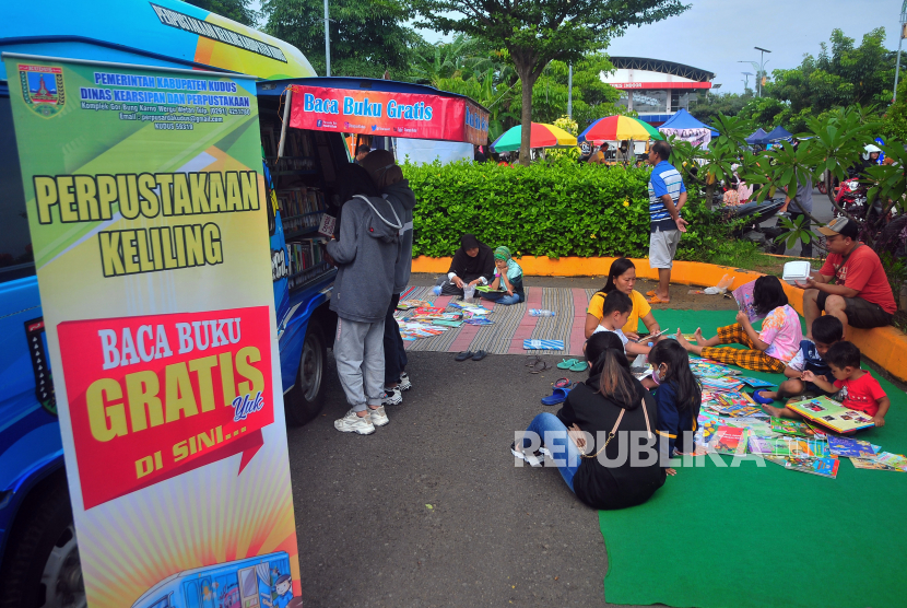 Sejumlah anak membaca buku di samping mobil perpustakaan keliling di fasilitas ruang terbuka Balai Jagong, Kudus, Jawa Tengah, Minggu (4/12/2022). Perpustakaan keliling yang difasilitasi Perpustakaan Daerah (Perpusda) setempat itu guna meningkatkan kebiasan membaca buku kepada masyarakat terutama anak-anak. 