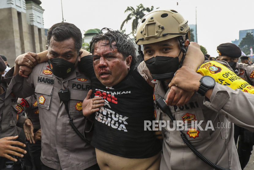 Pegiat media sosial Ade Armando (tengah) diamankan petugas kepolisian saat aksi unjuk rasa di depan kompleks Parlemen di Jakarta, Senin (11/4/2022). 