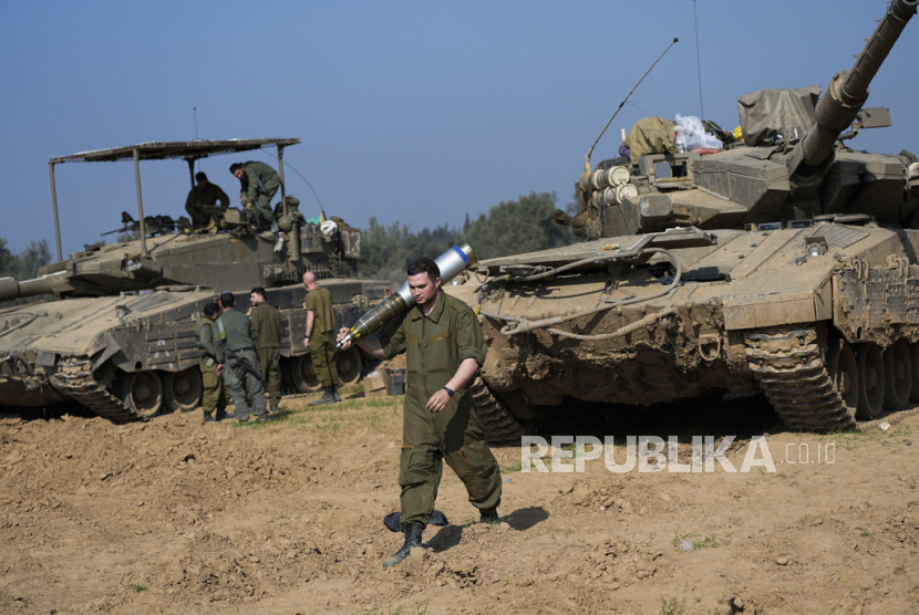 Seorang tentara Israel memasukkan peluru ke dalam tank di Israel selatan dekat perbatasan dengan Gaza pada Ahad, 31 Desember 2023.