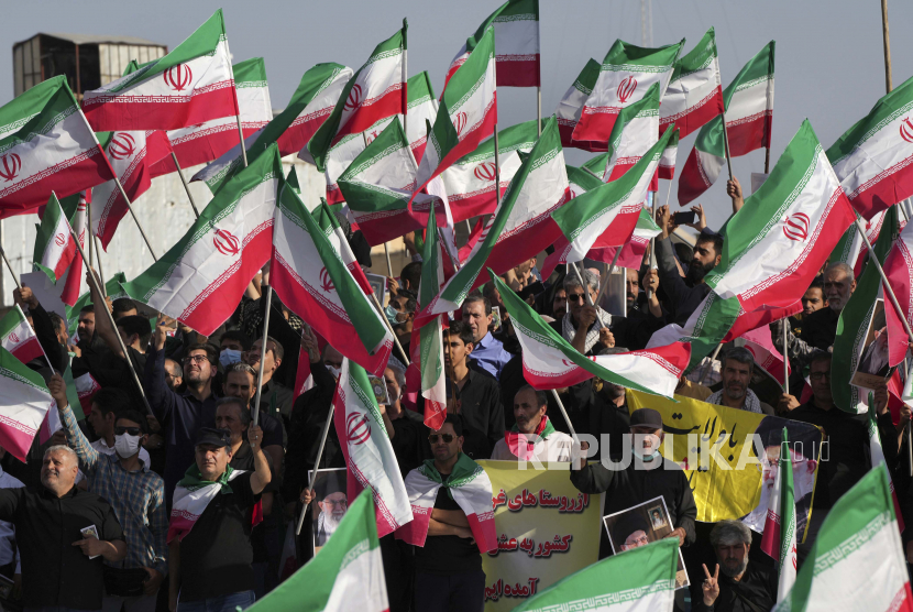 Demonstran pro-pemerintah mengibarkan bendera Iran selama rapat umum mereka mengutuk protes anti-pemerintah baru-baru ini atas kematian Mahsa Amini, seorang wanita berusia 22 tahun yang telah ditahan oleh polisi moral negara, di Teheran, Iran, Minggu, 25 September. , 2022.