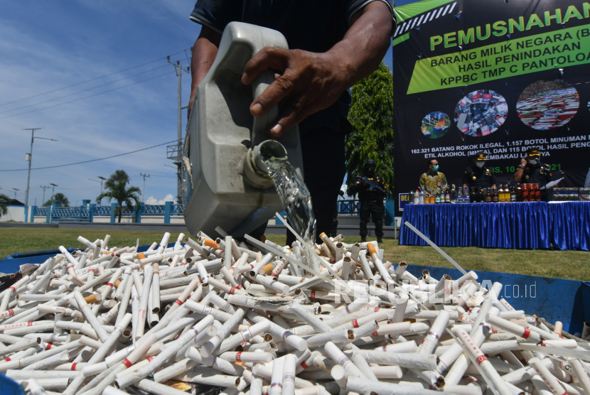 Petugas menuangkan minyak tanah ke tumpukan rokok ilegal hasil penindakan saat pelaksanaan pemusnahan di Kantor Pengawasan dan Pelayanan Bea Cukai (KPPBC) TMP C Pantoloan di Palu, Sulawesi Tengah, Kamis (10/6/2021). Sebanyak 162.321 batang rokok ilegal, 115 botol hasil penindakan pengolahan tembakau lainnya (HPTL) dan 1.157 botol minuman mengandung etil alkohol (MMEA) dimusnahkan. 