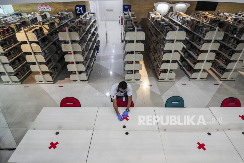 Petugas memasang tanda menjaga jarak fisik di Perpustakaan Nasional, Jakarta, Rabu (10/6). Perpustakaan Nasional menerapkan sejumlah protokol kesehatan menjelang pembukaan kembali pada Kamis (11/6) dan membatasi pengunjung sebanyak 1