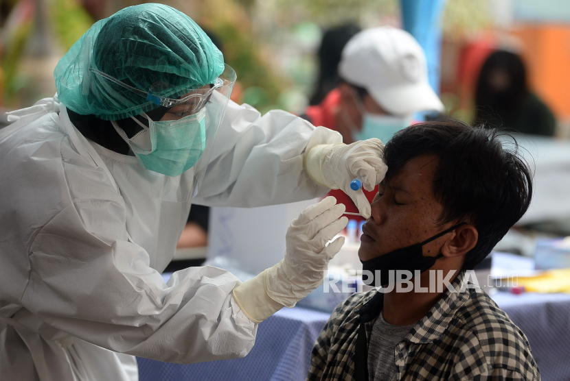 Petugas kesehatan melakukan tes cepat antigen kepada seorang penumpang yang baru tiba di Terminal Bus Kalideres, Jakarta.