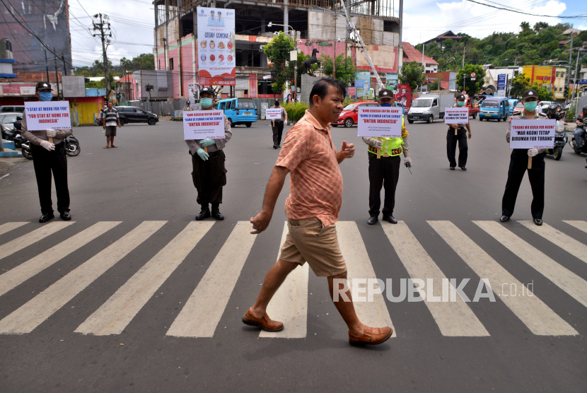 Anggota Polsek Tikala memegang spanduk imbauan di ruas jalan di Manado, Sulawesi Utara, Senin (30/3). (ilustrasi)
