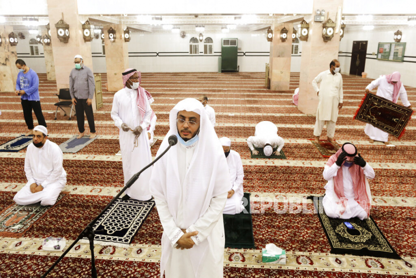 Muazin Masjid Al Mirabi Hammoud Al-Labban mengumandangkan azan dengan latar jamaah masjid yang mengenakan masker untuk menghindari wabah Covid-19, di Jeddah, Arab Saudi. Arab Saudi Angkat 25.714 Imam dan Muadzin
