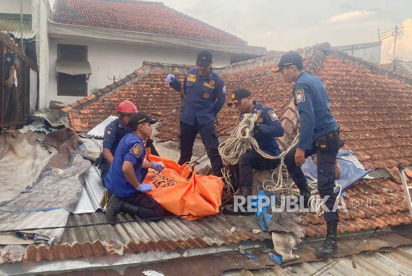 Petugas mengevakuasi warga yang ditemukan meninggal di atap rumah miliknya, di Jalan Muararajeun Baru, Kecamatan Cibeunying Kaler, Kota Bandung, Jawa Barat, Selasa (19/12/2023). 