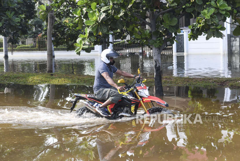 Pengendara motor melintas saat banjir rob menggenangi Kompleks Pantai Mutiara, Penjaringan, Jakarta, Ahad(7/6/2020). Banjir di kawasan tersebut diduga akibat adanya tanggul yang jebol saat naiknya permukaan air laut di pesisir utara Jakarta