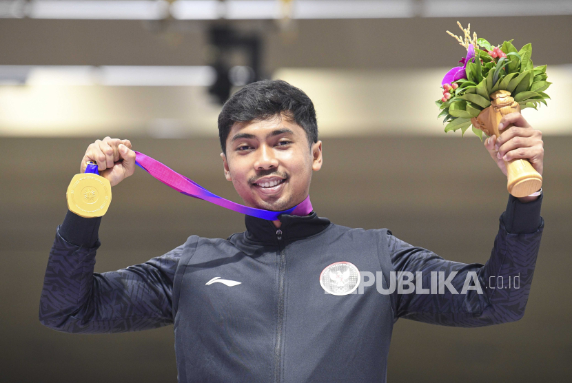 Petembak tunggal putra Indonesia Muhammad Sejahtera Dwi Putra berpose dengan medali emas Asian Games 2022. Raihan medali emas dari cabang menembak, posisi Indonesia bertahan di 10 besar.