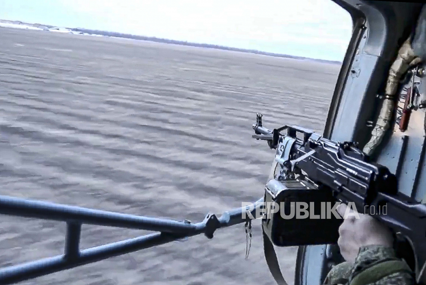 Dalam foto yang diambil dari video yang dirilis oleh Layanan Pers Kementerian Pertahanan Rusia pada Selasa, 1 Maret 2022, seorang tentara Rusia menodongkan senjata dari helikopter militer Rusia saat terbang di atas lokasi yang dirahasiakan di Ukraina. 