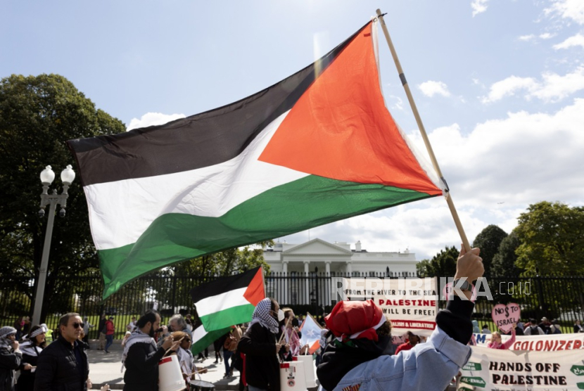 Seorang warga membawa bendera Palestina saat aksi unjuk rasa untuk memberikan dukungan bagi rakyat Palestina di depan Gedung Putih, Ahad (8/10/2023) waktu setempat. Massa mendesak dihentikannya penjajahan Palestina oleh zionis Israel yang menyebabkan konflik berkepanjangan di kawasan tersebut.