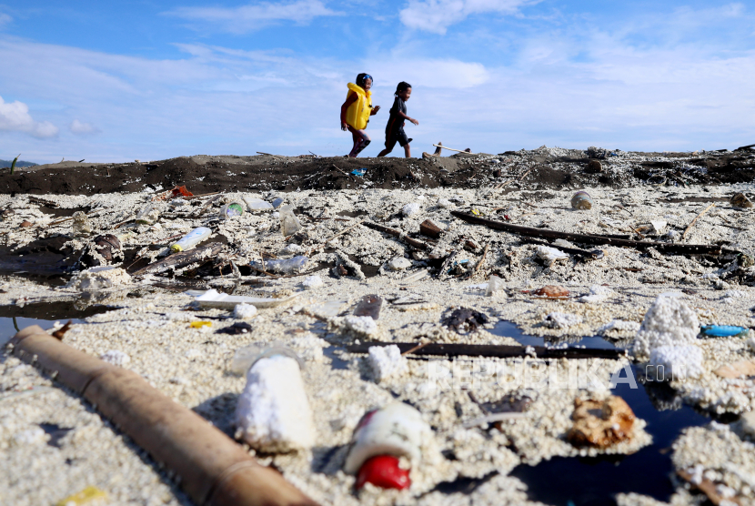 Dua anak bermain di kawasan pantai yang dipenuhi sampah di Pantai Manakarra, Mamuju, Sulawesi Barat, Ahad (7/7/2024). 