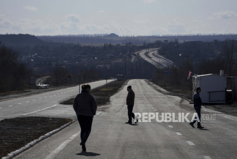 Orang-orang berjalan di dekat pos pemeriksaan antara wilayah yang dikendalikan oleh separatis yang didukung Rusia dan wilayah yang dikendalikan oleh pasukan Ukraina di Novotroitske, Ukraina timur, Senin, 21 Februari 2022. 