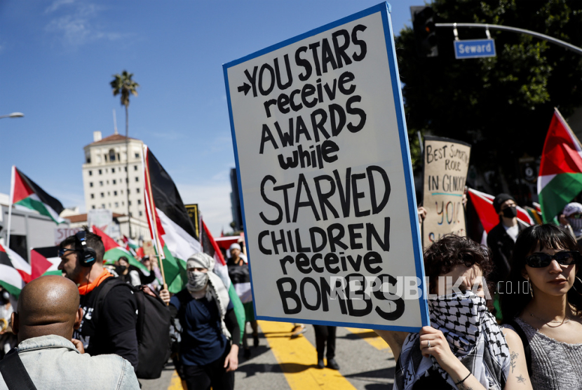 Seorang pengunjuk rasa memegang poster saat demonstrasi mendukung warga Palestina yang menyerukan gencatan senjata di Gaza, dekat Teater Dolby tempat upacara Oscar Academy Awards ke-96 diadakan di kawasan Hollywood Los Angeles, Ahad (10/3/2024).