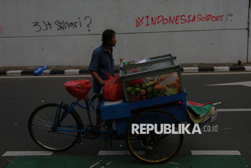Pedagang melintas di depan dinding bertuliskan Indonesia Sold Out saat aksi dari berbagai elemen masyarakat di Jalan Gerbang Pemuda, Jakarta, Senin (25/8/2025). Aksi demonstrasi massa kembali terjadi pada Jumat (29/8/2025).