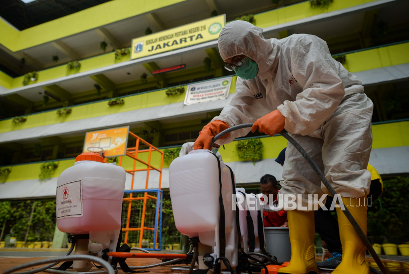 Petugas Palang Merah Indonesia Kota Jakarta Pusat menyemprotkan cairan disinfektan di SMP 216 Jakarta Pusat, Senin (16/3/2020).
