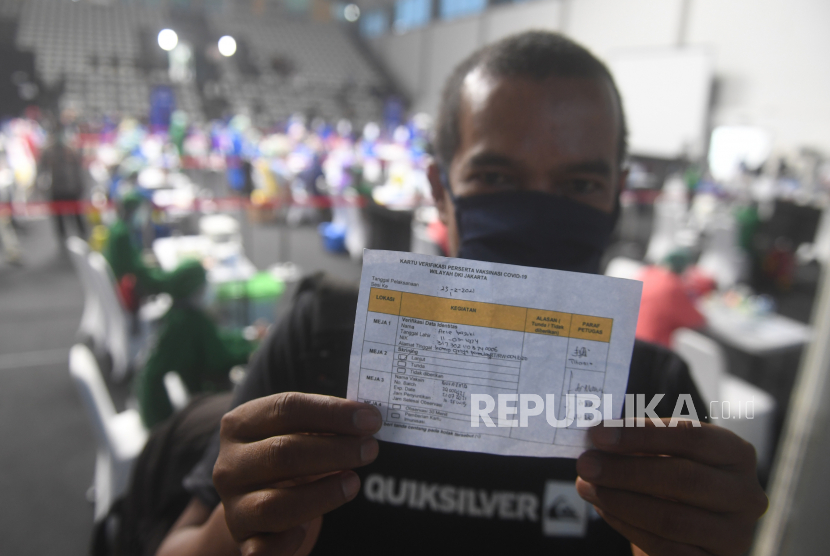 Seorang wartawan menunjukkan kartu verifikasi peserta vaksinasi COVID-19 di Hall Basket, Senayan, Jakarta, Kamis (25/2/2021). Sebanyak 5.500 awak media di Jakarta akan menerima vaksin COVID-19 secara bertahap. 