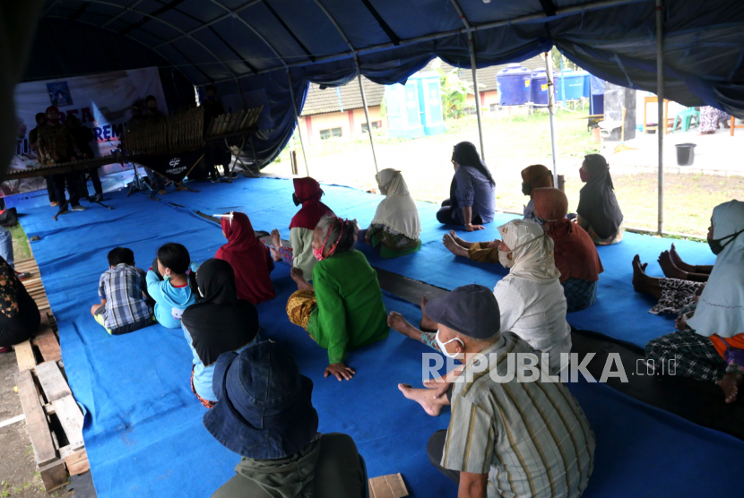 Pengungsi menonton pertunjukan musik angklung di Barak Pengungsian Glagaharjo, Sleman, Yogyakarta, Ahad (29/11). Pertunjukan kesenian ini diadakan untuk menghibur pengungsi. Tetapi, penampilan grup kesenian tampil secara berkala dan suka rela.