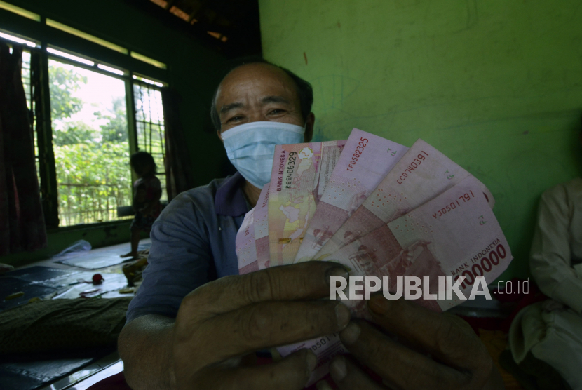 Warga menunjukkan uang tunai saat penyaluran Bantuan Sosial Tunai (BST). (ilustrasi)