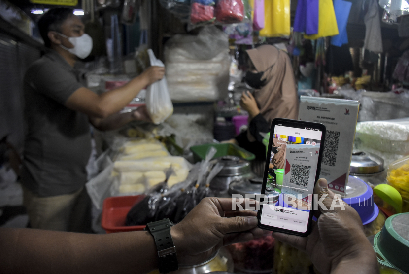 Warga melakukan pembayaran menggunakan QRIS di salah satu kios di Pasar Kosambi, Kota Bandung, Jawa Barat, Senin (10/7/2023).